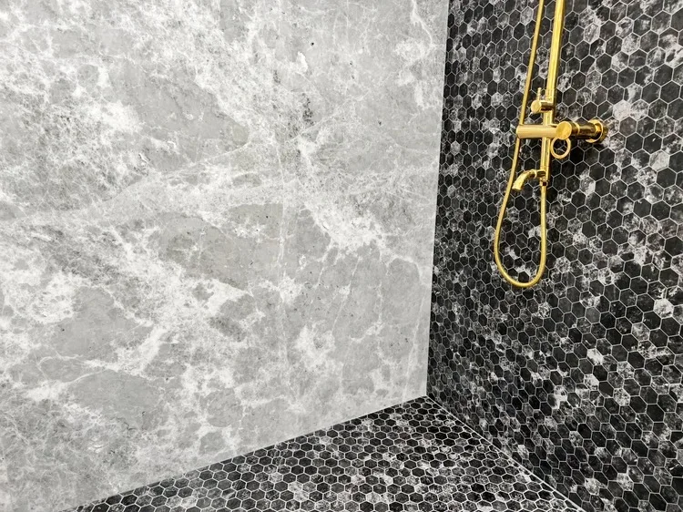 Marble wall tile and black hexagon floor tile shower with gold fixtures