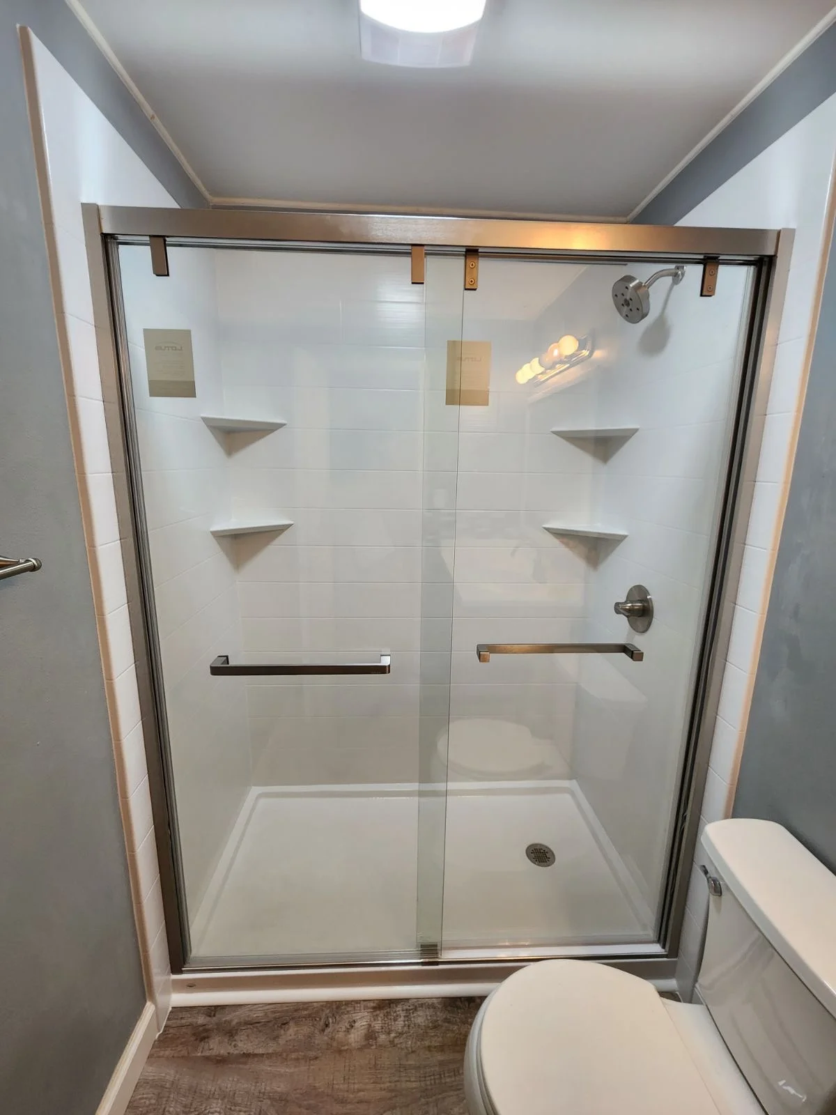 Frameless glass shower with white subway tile, brushed nickel fixtures, and built-in niches
