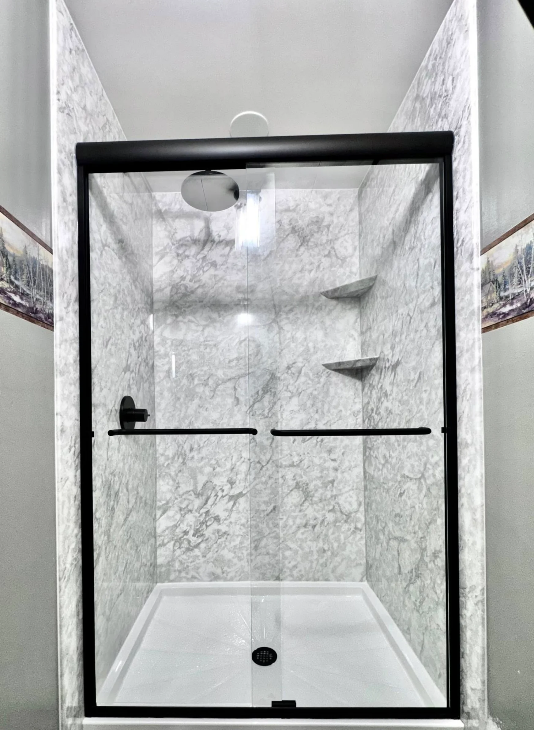 Gray marble tile shower with black-framed glass sliding doors and dual showerheads