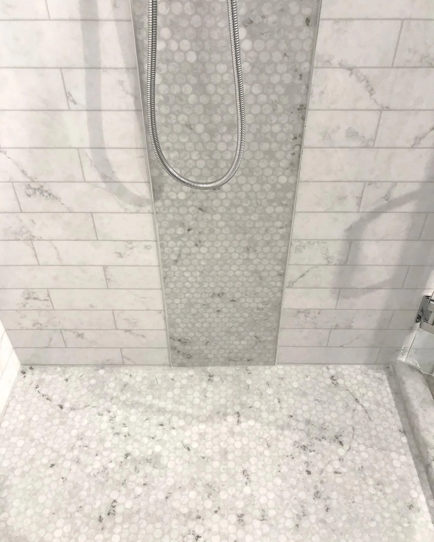 Marble subway tile shower walls with vertical penny tile accent strip and matching penny tile floor