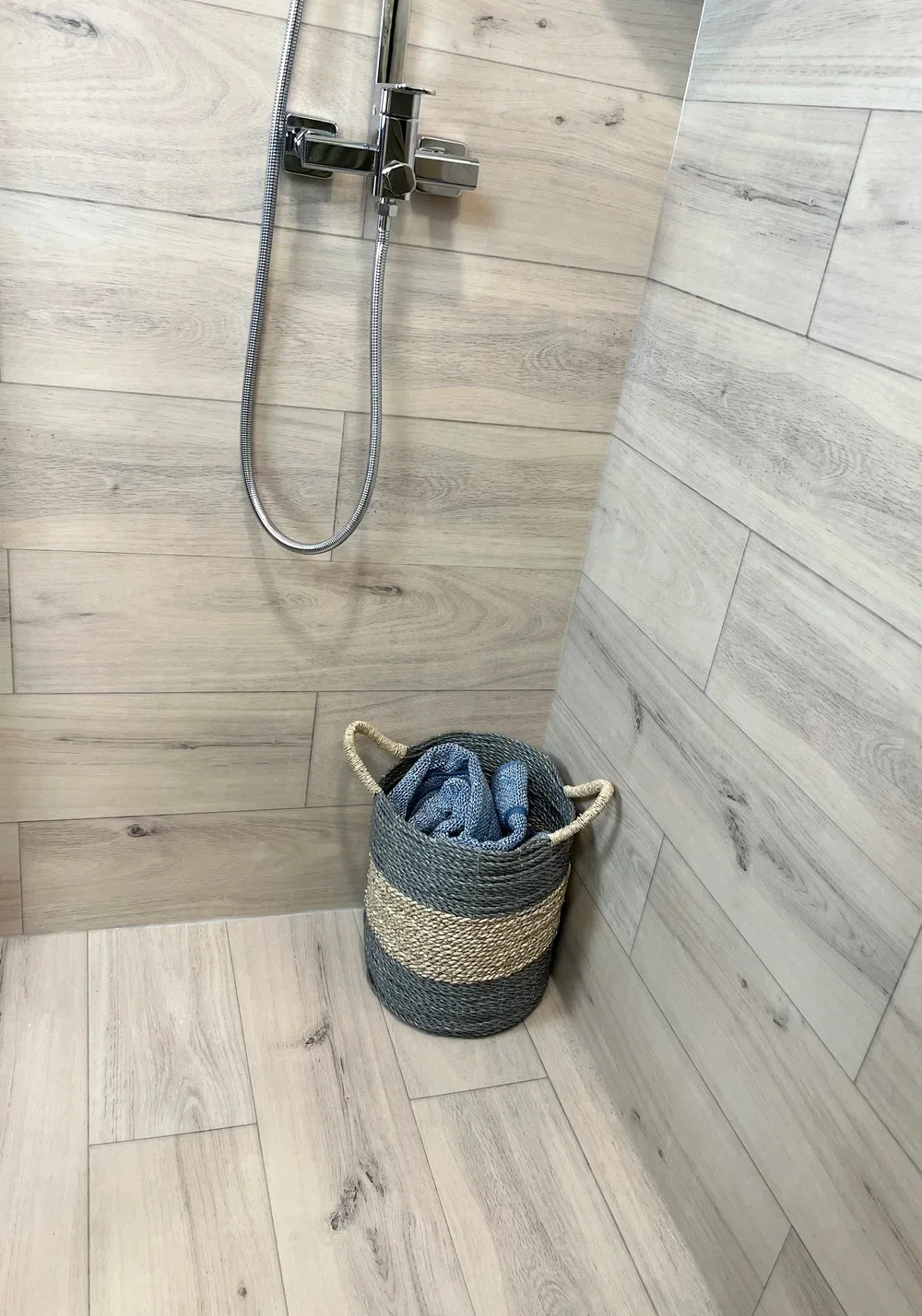 Wood-look porcelain tile shower with chrome fixtures and handheld showerhead
