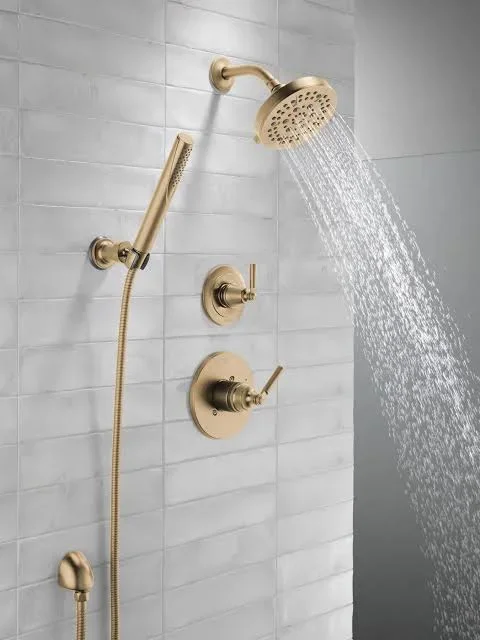 Champagne bronze shower system with rainfall head, handheld wand, and dual controls on white subway tile