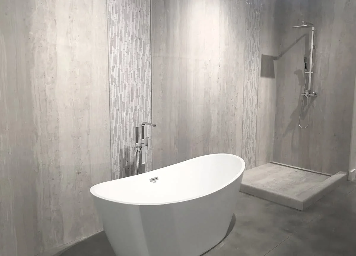 Freestanding white tub and walk-in shower with linear tile walls and concrete flooring