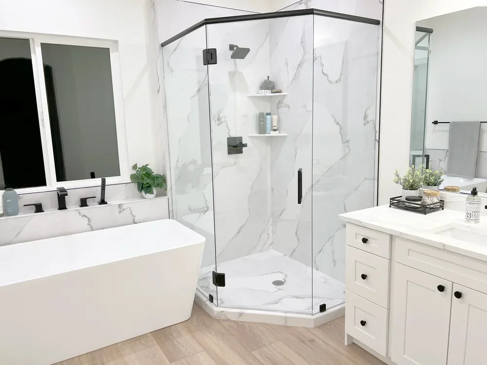 Frameless glass shower with marble tile, freestanding tub, and dual vanity bathroom